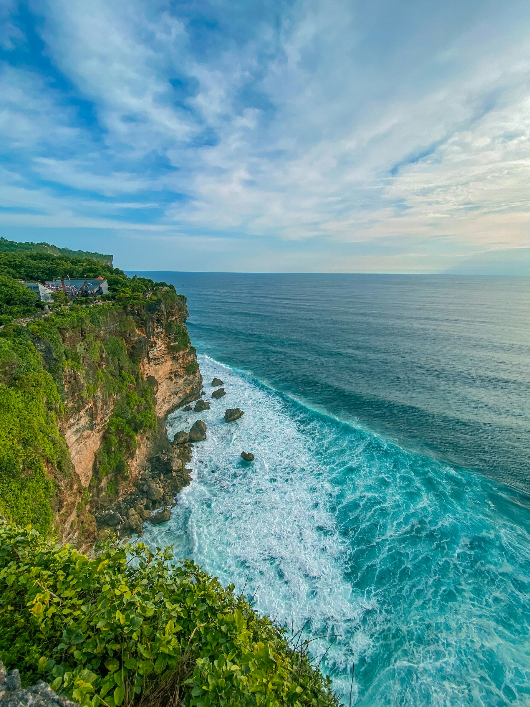 Green limestone cliffs meeting the blue ocean in Bali